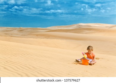 Two years old baby girl playing in a desert like in big sandbox