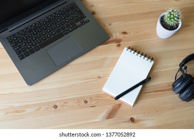 Maqueta de escritorio y escena de escritorio empresarial. Maqueta de portátil y escritorio de madera de oficina con portátil, smartphone, bloc de notas y planta de cactus. Cuaderno oscuro con gráfico de ventas en pantalla.