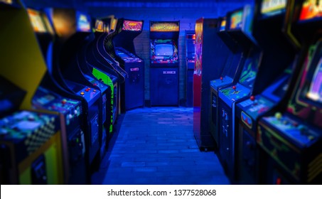 Old Vintage Arcade Video Games in an empty dark gaming room with blue light with glowing displays and beautiful retro design on a wide landscape photo