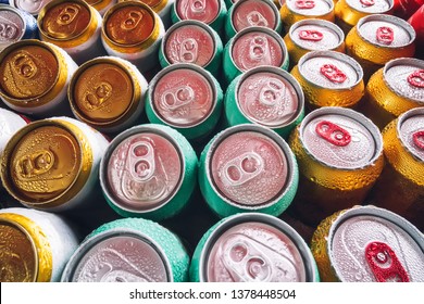Latas metálicas de cerveza con cubitos de hielo en mini refrigerador, de cerca. Montones de latas de aluminio en el hielo de la nevera abierta. Gotas de agua en una lata de bebida fría.