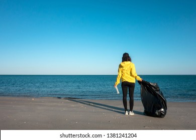 Femeie care ridică gunoi și materiale plastice curățând plaja cu un sac de gunoi. Activist voluntar de mediu împotriva schimbărilor climatice și a poluării oceanelor.