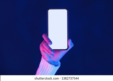 Frauenhand zeigt Smartphone-Bildschirm in neonblauem und pinkfarbenem Licht