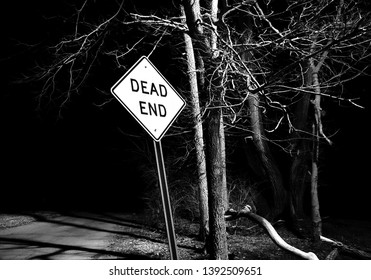 Dead end sign with trees on creepy street in black and white