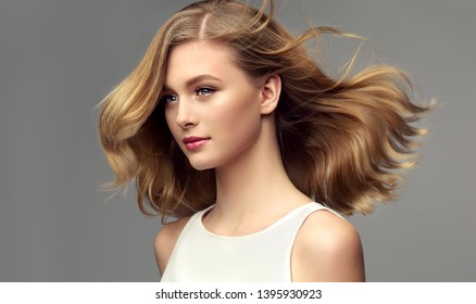 Blondevrouw met mooi krullend haar op grijze achtergrond. Het meisje met een prettige glimlach. Kort kapsel . Bob kapsel
