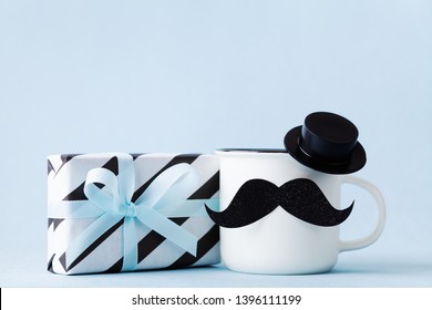Creative breakfast on Happy Fathers Day with gift or present box and funny face from cup of coffee, hat and moustache.