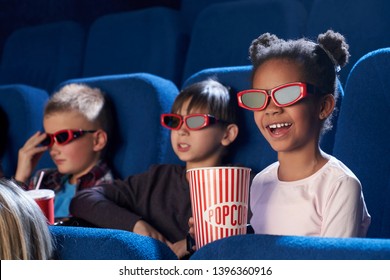 Gelukkig kind met 3D-bril, lekkere popcorn etend en komische film kijkend. Schattig klein meisje dat haar vrije tijd met vrienden in de bioscoop doorbrengt en lacht. Concept van vrije tijd en entertainment.