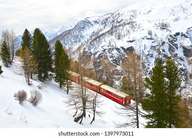 A local red train passing by Alp Grum station below Bernina express railway, Switzerland
