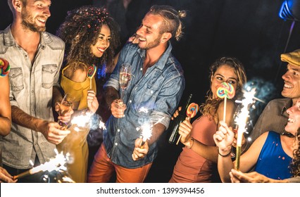 Teman multirasial bersenang-senang di festival musim panas Orang-orang muda minum dan menari setelah pesta di klub malam Konsep persahabatan pada suasana hati yang bersemangat Fokus pada wajah pria jeans biru