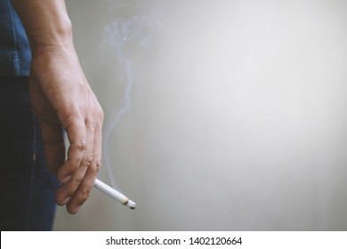 Mann, der eine Zigarette in der Hand raucht. Zigarettenrauch breitete sich aus. dunkler Hintergrund