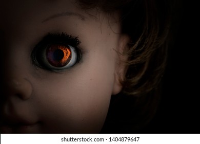 Close-up scary vintage doll face isolated on black background. Soft backlight, focus on eye. Halloween concept