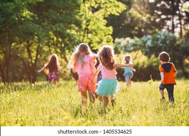 Một nhóm lớn trẻ em, bạn bè chàng trai và cô gái chạy trong công viên vào ngày hè đầy nắng trong trang phục giản dị