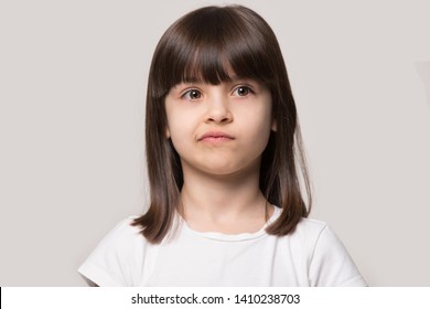 Molesto cabello castaño flequillo peinado niña pequeña fruncir la boca se siente molesto o insatisfecho retrato de estudio de disparo en la cabeza sobre fondo beige, concepto de niño travieso, ansiedades del concepto de persona pequeña