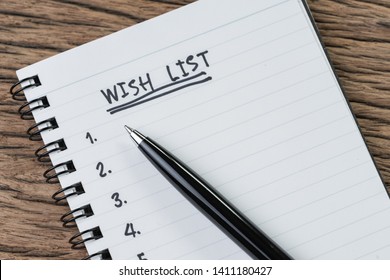 Wish list concept, pen on white paper note pad with handwritten headline as Wish List and numbers listed on wood table in soft tone, things wanted or next time purchase.