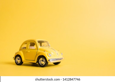 Omsk, Russia - May 26, 2019: Yellow retro toy car on yellow background. Valentine's day. Flower delivery. 8 March, International Happy Women's Day. Summer travel concept. Taxi