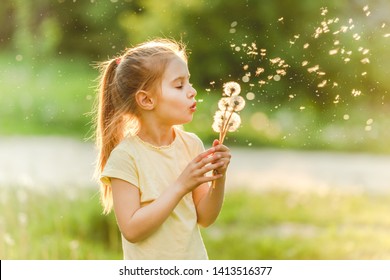 Beatiful girl child loves to spend her leisure at meadow, collecting flowers and playing with dandelions