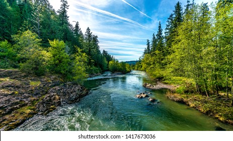 A bright blue river flowing through an Oregon forest as the sun begins to set in a hidden park along the scenic drive in southern Oregon, northern California border.