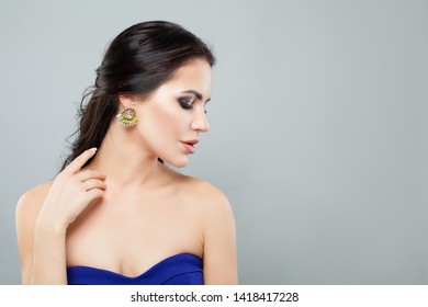Porträt einer schönen Frau in modischen Schmuckohrringen mit grünem Edelstein und Diamant. Weibliches Profil