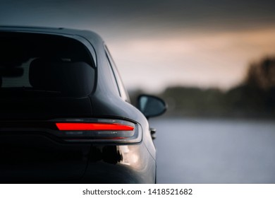 夕方の現代のSUV車のリアテールランプ。日没時の夕方のモダンなクロス オーバーの裏側。テールライトのバックライトが点灯