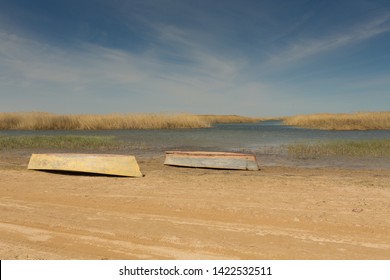 Ein Boot wurde auf den Kopf gestellt. Ruderboote im Schilf. Holzboot an einem grasbewachsenen Seeufer an einem Sommertag. Aralsee, Kasachstan
