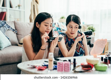 Groep leuke vriendinnen maken zich klaar en doen make-up op voordat ze 's avonds naar een verjaardagsfeestje gaan in de woonkamer thuis. Jonge meisjes brengen cosmetica aan op hun gezicht voor een date.