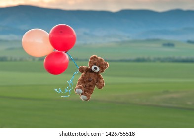 Oso de peluche volando hacia el cielo con grandes globos amarillos y rojos. Un oso vuela sobre los campos. Viaje en globo Pooh.