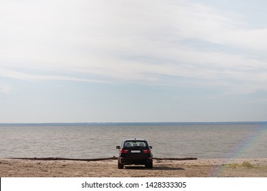 a parked car by the blue sea on a sandy beach