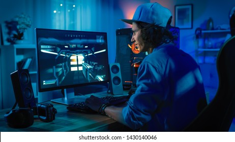 Professionele gamer speelt first-person shooter online videogame op zijn krachtige personal computer met kleurrijke neon led-verlichting. Jonge man draagt een pet. Woonkamer verlicht in rustige stijl. Avond