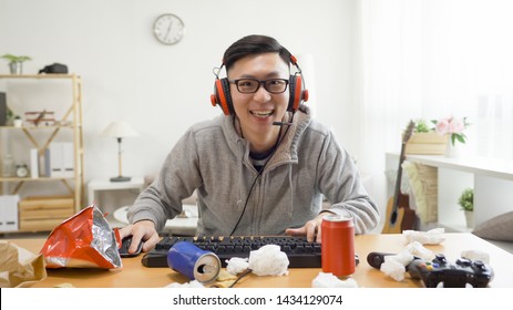 ゲーム ビデオ ゲーム コンピューターのコンセプト。アジアの10代の少年が、夏休みに家に座ってキーボードとヘッドフォンでフットボールの試合をしている。メガネ近視で中毒の若い男