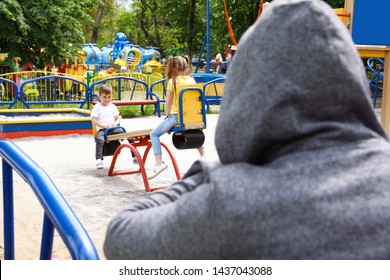Pria dewasa yang mencurigakan memata-matai anak-anak di taman bermain, ruang untuk teks. Anak dalam bahaya