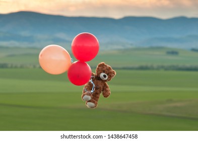 Teddybär fliegt mit großen gelben und roten Luftballons in den Himmel. Ein Bär fliegt über die Felder. Puuh Ballonfahrt. Flugreisen.