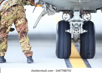 Een legermonteur inspecteert het landingsgestel van een militair vrachtvliegtuig.