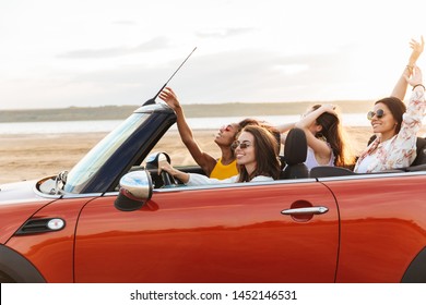 車を運転している驚くべきかなり肯定的な笑顔の陽気な若いきれいな女性の友人の画像が手を上げました。