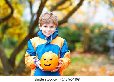 Happy cute little kid boy with halloween pumpkin lantern. Funny child in colorful clothes having fun and playing in autumn garden on cold autumnal day. Scary jack-o-lantern, celebration of holiday.