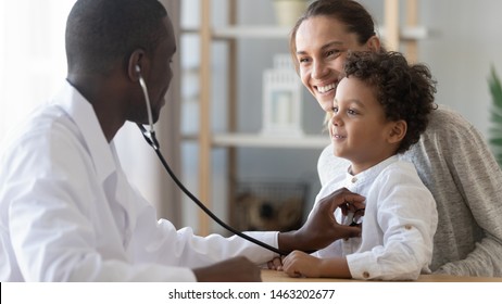 Afrikansk mandlig børnelæge holder stetoskopeksamen barn dreng patient besøg læge med mor, sort børnelæge tjekke hjerte lunger af barn gør pædiatrisk kontrol på hospital børn lægebehandling koncept