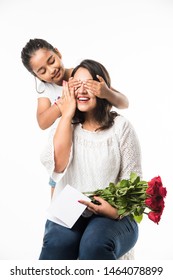 母の日 – バラの花の花束で母の日を祝うインドの女の子/母、抱き合い、キスをしながらグリーティングカード