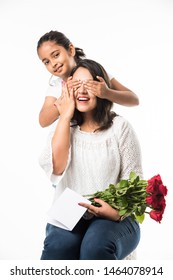 Mors dag - Indisk pige / mor fejrer mors dag med rosenblomstbuket, lykønskningskort, mens du krammer og kysser hinanden