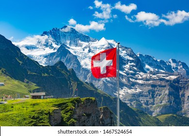 Schweizer Fahnenschwingen und Touristen bewundern die Gipfel der Berge Mönch und Jungfrau auf einem männlichen Aussichtspunkt, Berner Oberland Schweiz