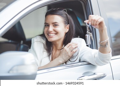 Young attractive woman just bought a new car. female holding keys from new automobile.