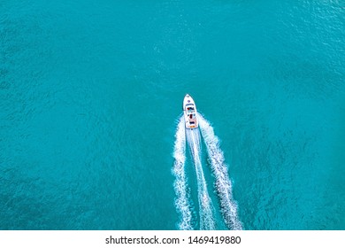 Perahu cepat di laut biru dengan air biru kehijauan - pemandangan udara perahu