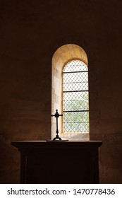 Cross silhouette on altar near window in dark empty old chapel. Game of light and shadow in church. Religious christian background. Despair and hope, divine mercy, god love concept.