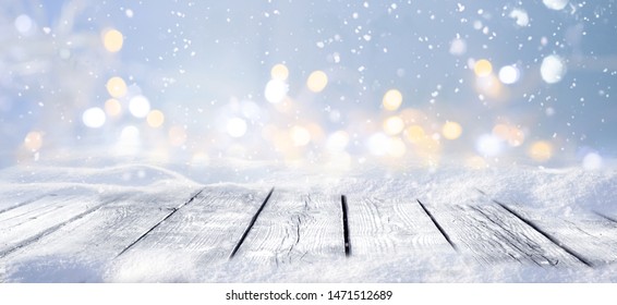 Fondo de escenario nevado de invierno con suelo de madera y luces de Navidad sobre fondo azul, formato de banner, espacio de copia.