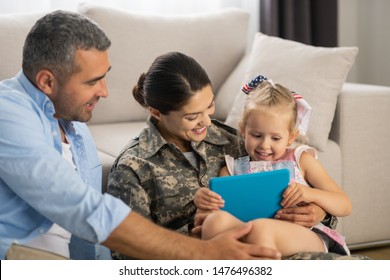 Unbelievably happy. Military woman feeling unbelievably happy watching cartoon with daughter and husband
