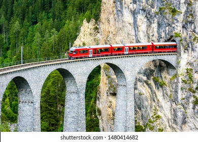 Bernina express trên Landwasser Viaduct, Thụy Sĩ. Nó là cột mốc của dãy núi Alps của Thụy Sĩ. Tàu băng đỏ chạy từ đường hầm xuyên núi trên cầu cao. Nhìn từ trên không của đường sắt vào mùa hè. Khái niệm đường sắt.