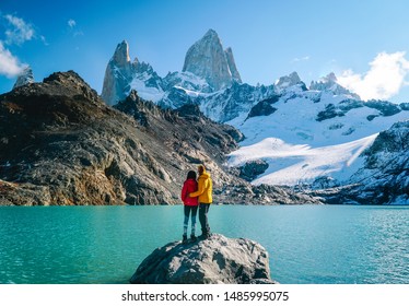 Verliefd stel en schilderachtig uitzicht op besneeuwde bergtoppen van Mount Fitzroy, trektocht door Patagonië. Blauwe lucht, turkoois meer en schilderachtig rotslandschap. Geschoten in Argentinië. Natuur, reizen, avontuur, wandelen.