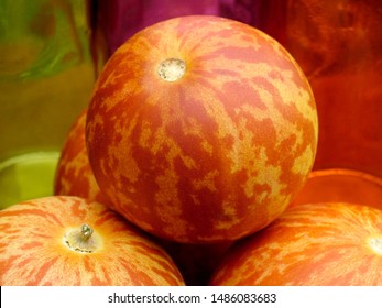 Vertikale Nahaufnahme der gestreiften, orangefarbenen Früchte der 'Tigger'-Melone, einer Erbstücksorte, die sowohl essbar als auch duftend ist