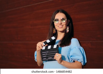 Coole Schauspielerin, die Filmklöppel zum Filmen bereit hält. Weibliches Model mit Werbespot für Filmaufnahmen