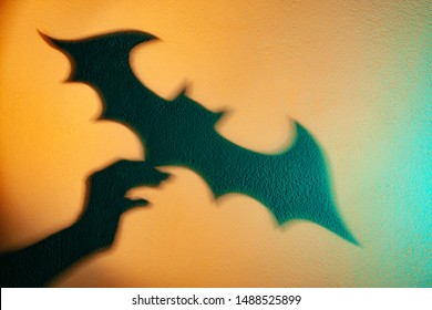 Mano sosteniendo un bate. Reflexión de la sombra en la pared. Teatro de sombras. El Símbolo De Víspera De Todos Los Santos. Sombra de murciélago en la pared. Hombre murciélago.