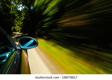 Zrcadlový pohled na černé auto v lese.