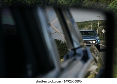 Stari avto v vzvratnem ogledalu. Klasični avtomobili si sledijo na cesti. Po ulici vozi star avto, ki uživa v poletju. Ford Thunderbird in Lincoln