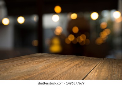 Leeg houten tafelblad op vervaging licht gouden bokeh van café-restaurant in donkere achtergrond
